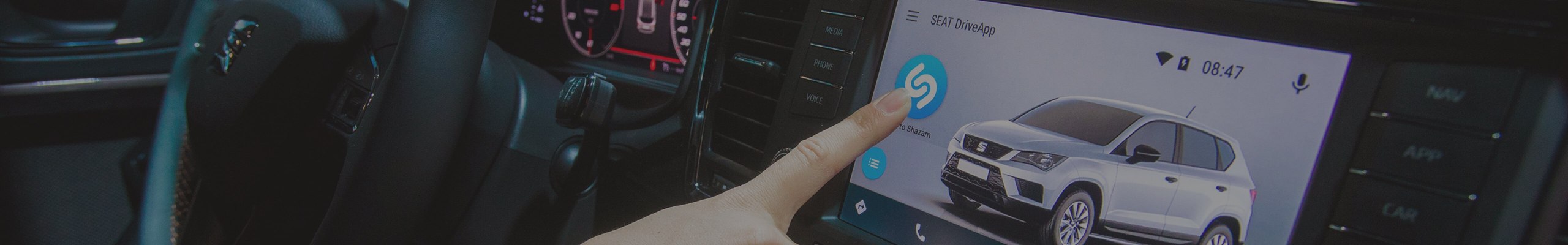 Palec dotykający dotykowej konsoli z włączoną aplikacją Shazam w modelu SEAT-a