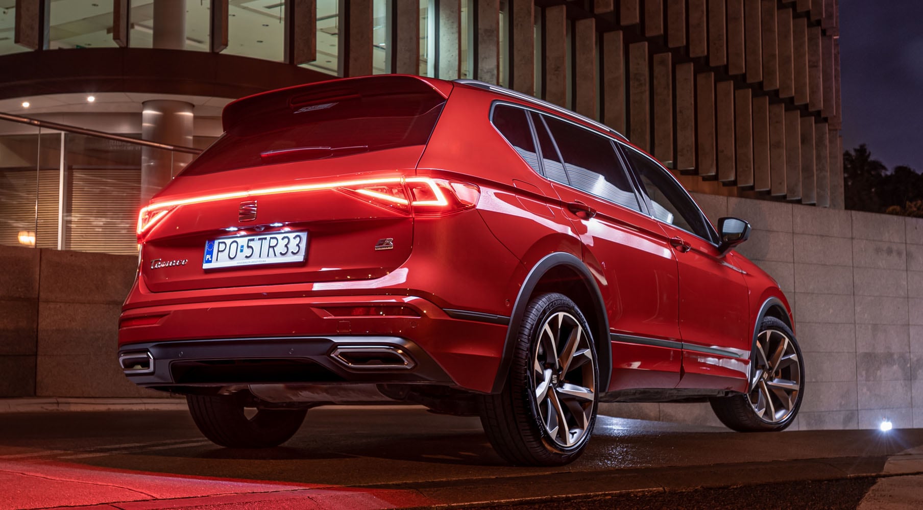 Seat Tarraco  w kolorze Desire Red z zapalonymi tylnymi światłami LED podczas parkowania