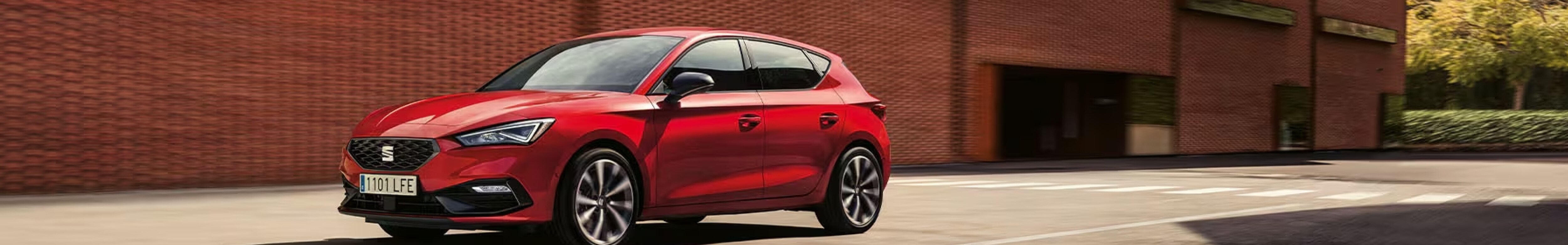 Hybrydowy SEAT Leon typu plug-in w kolorze Desire Red, jadą cy ulicami miasta