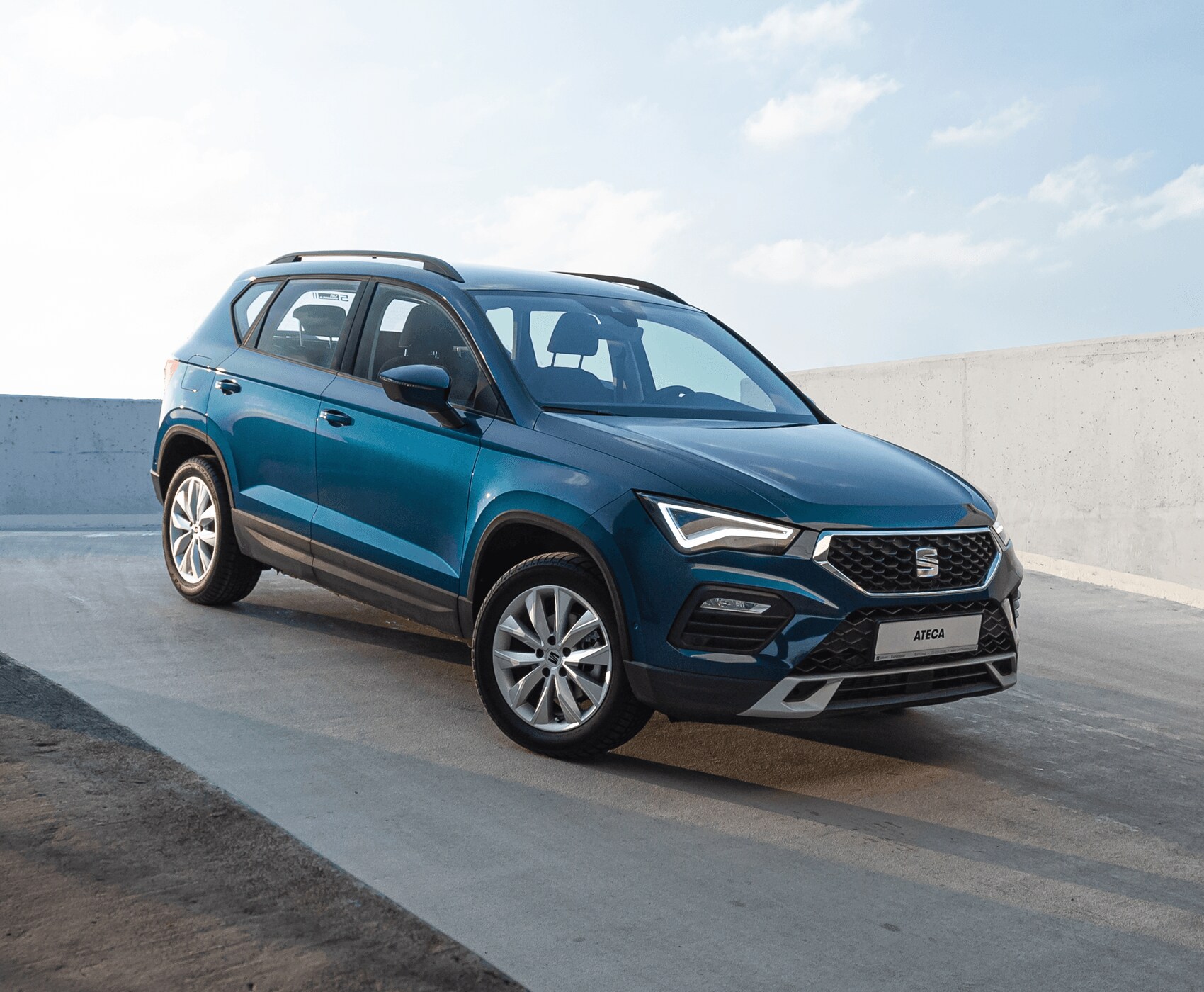 SEAT Arona w kolorze Lava Blue, metalizowany z zapalonym reflektorem LED. Widok z przodu na prawy profil. 