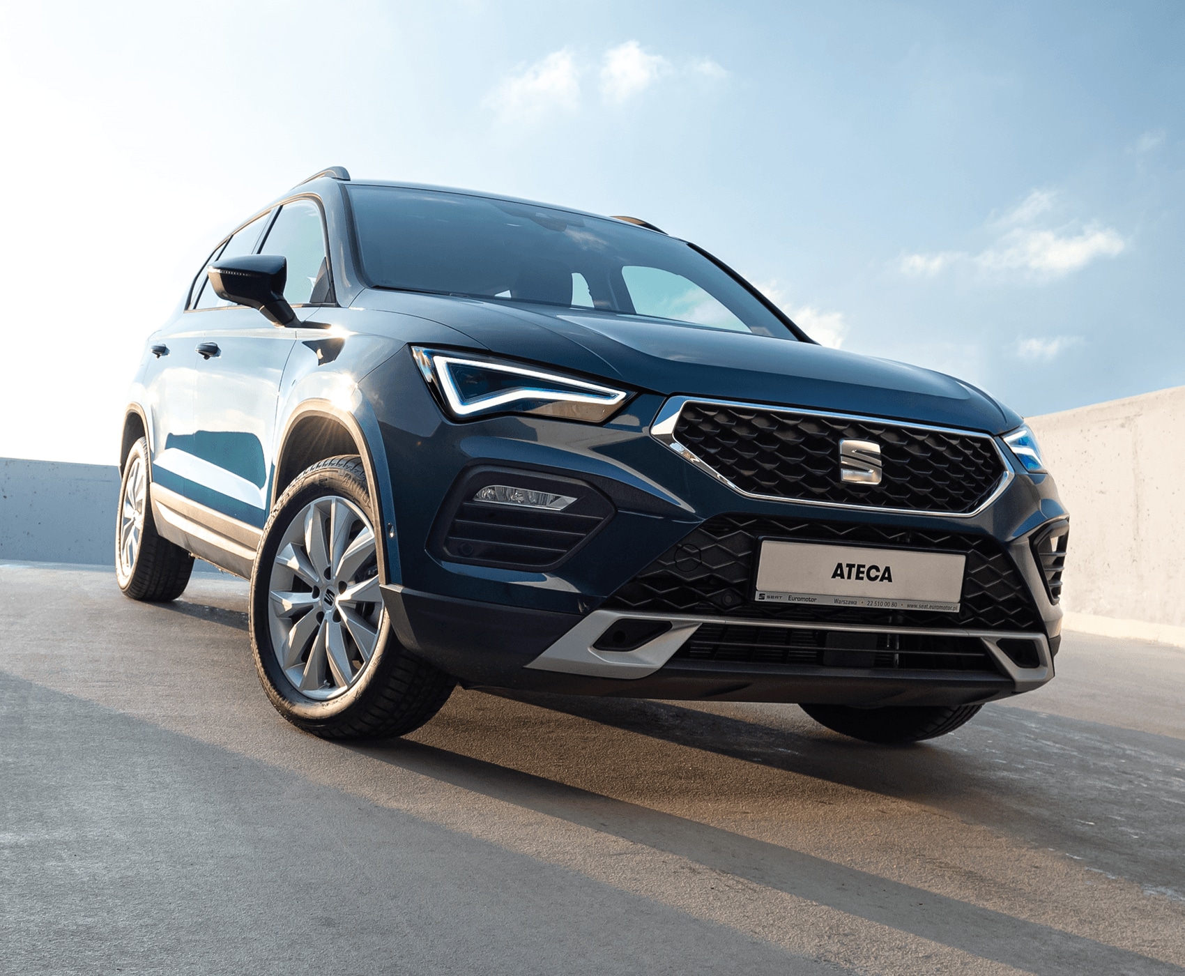 Zaparkowany SEAT Arona w kolorze Magnetic Tech, metalizowany. Widok z przodu na prawy profil. Światło dzienne. 