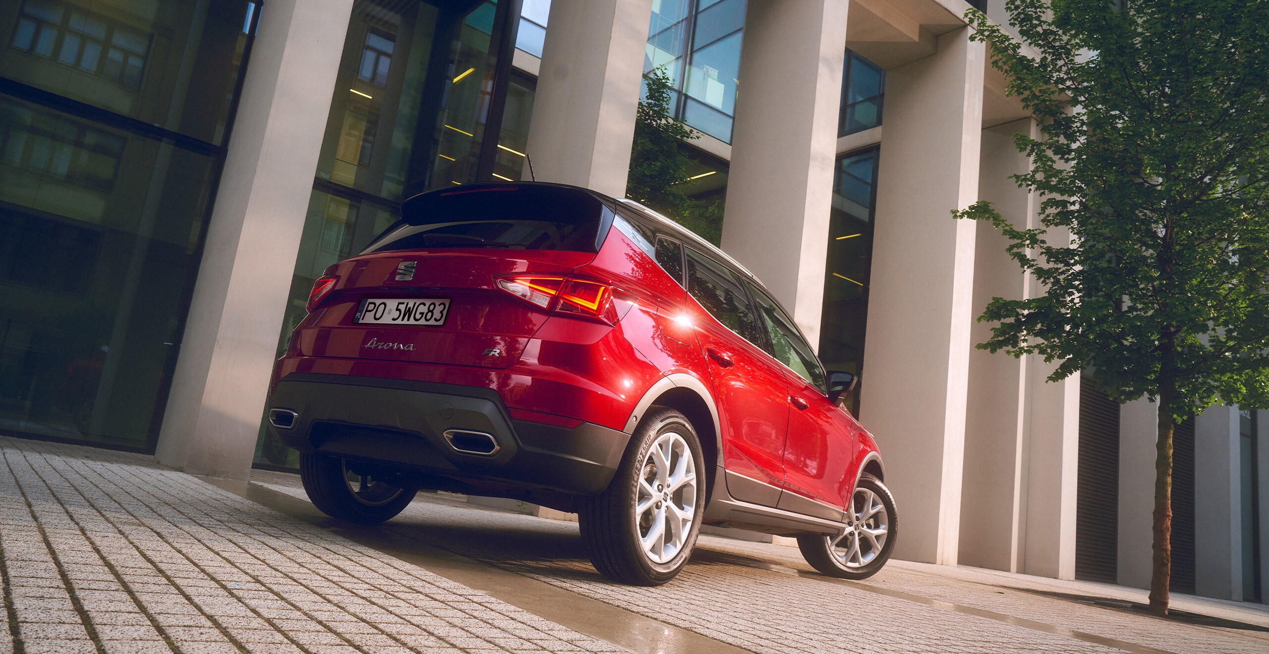 Zaparkowany SEAT Arona w kolorze Lava Blue, metalizowany, widok od tyłu, lewy profil. W świetle dziennym.