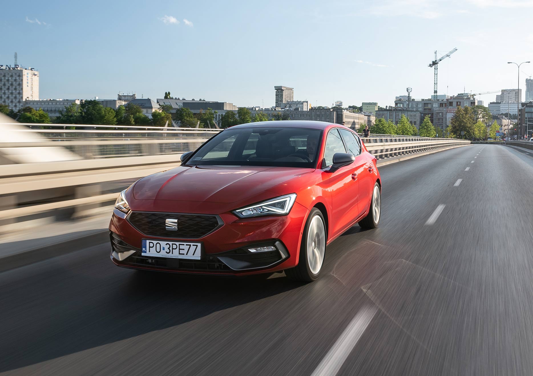 Leon hatchback w kolorze Desire Red na pustynnym terenie, widok z prawego boku