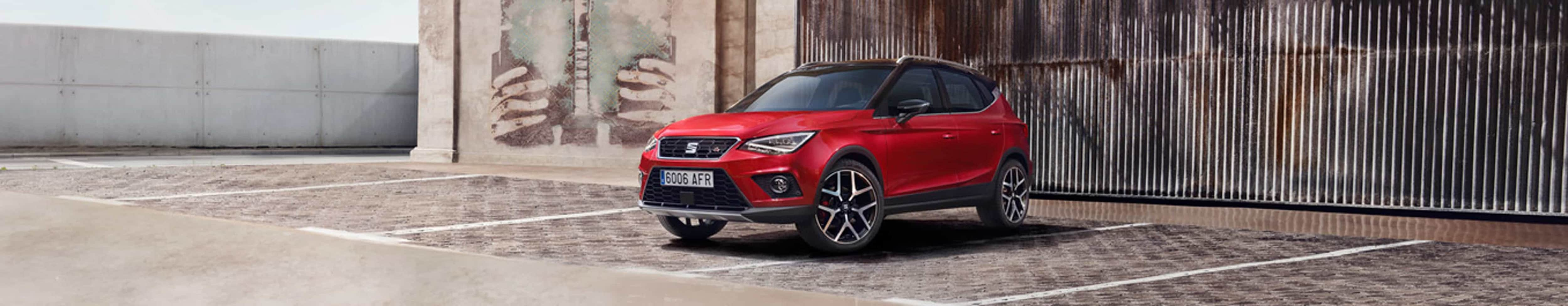 SEAT Arona FR w kolorze Desire Red w miejskim otoczeniu, widok z przodu