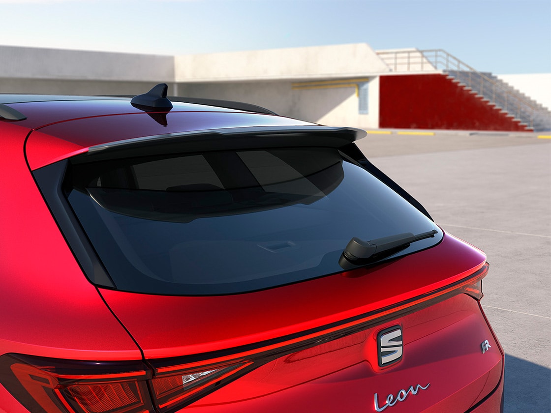 Czerwony SEAT Leon ze sportowym spojlerem dachowym, poprawiającym aerodynamikę i osiągi w podstawowych i zaawansowanych wersjach wyposażenia.