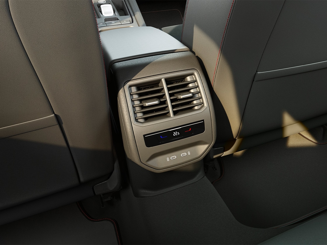 Widok wnętrza z tyłu SEAT-a Leon Sportstourer, prezentujący elementy pakietu wygodnego: 3-strefową klimatyzację Climatronic, gniazda USB-C oraz centralny podłokietnik.