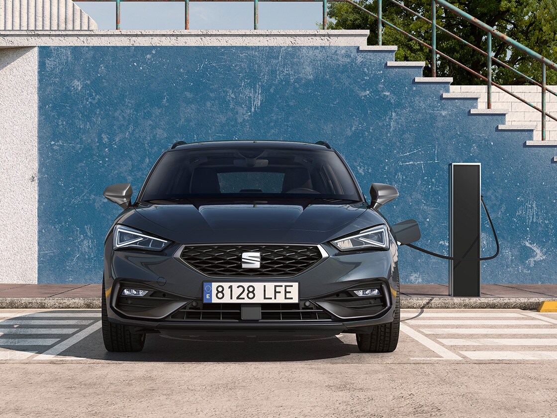 seat leon sportstourer e hybrid, hybrydowy samochód elektryczny, zaparkowany na miejscu parkingowym obok stacji ładowania na zewnątrz, prezentujący funkcję e manager o imponującej wartości.