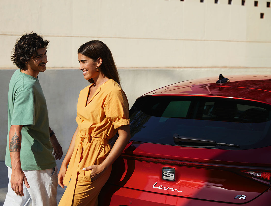 Para rozmawiająca obok samochodu marki SEAT. Dobrze widoczne logo samochodu i zintegrowane tylne światła LED