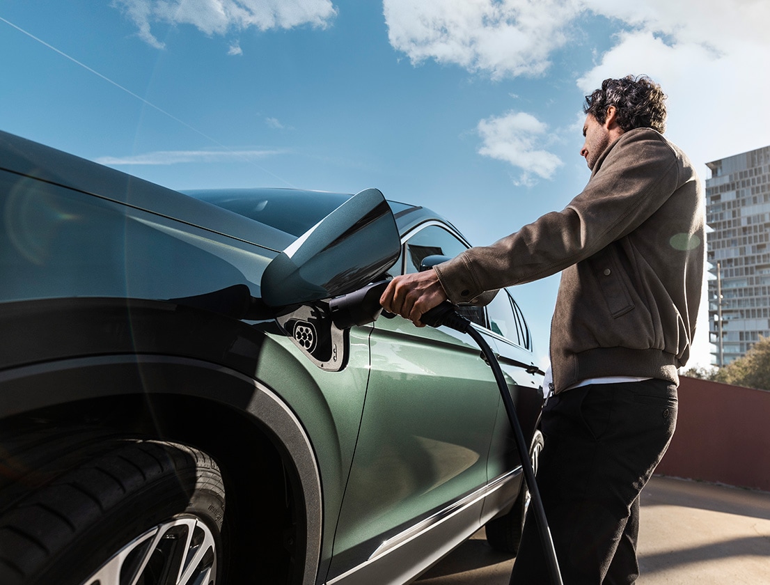 Man charging a SEAT Tarraco XPERIENCE e-HYBRID Dark Camouflage colour   