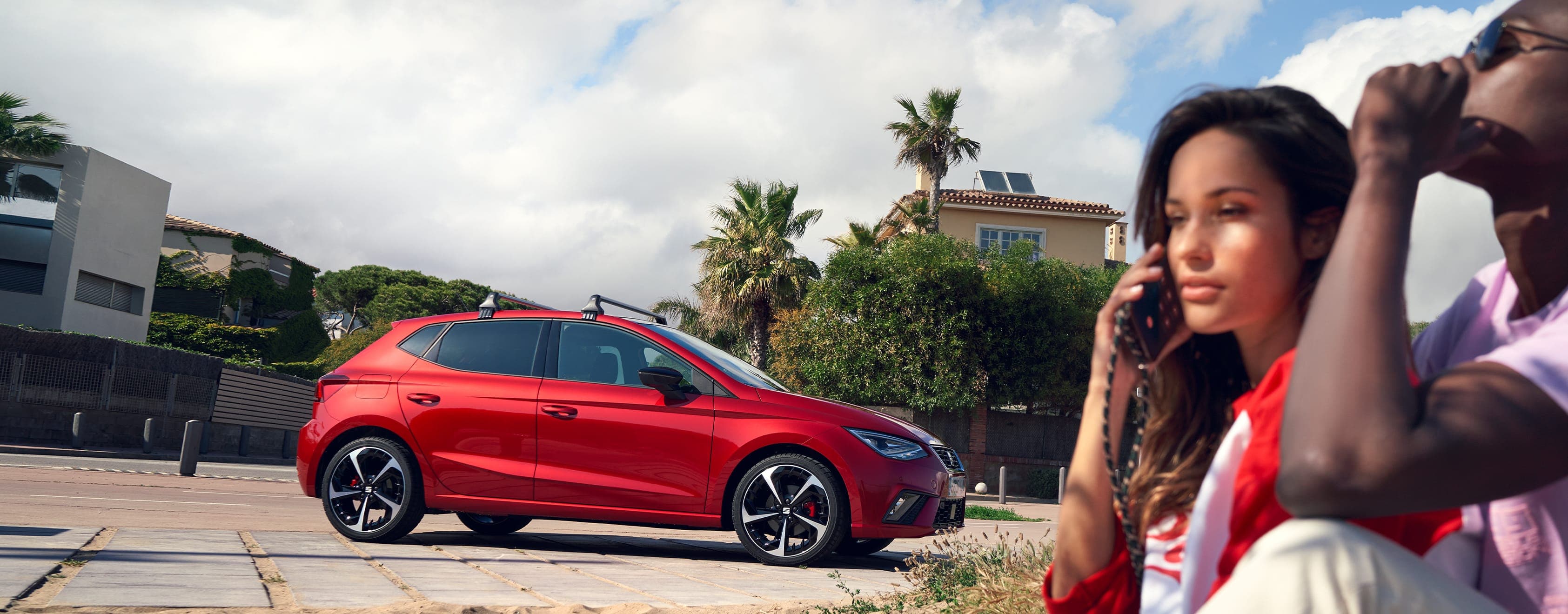 Para dzwoni po pomoc drogową siedząc obok SEATa Ibiza w kolorze desire red