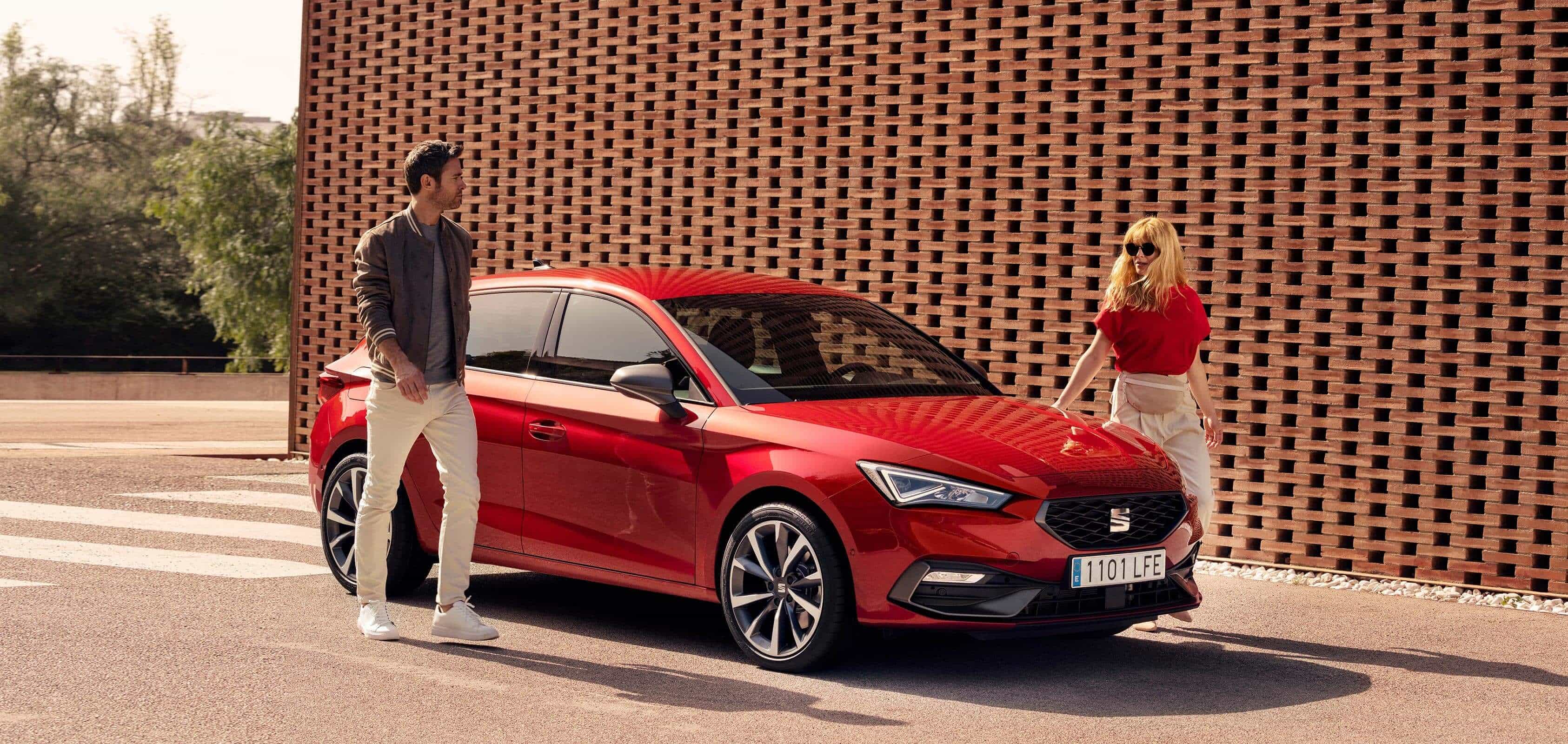 Para stojąca przy nowym SEATcie Leonie w kolorze Desire Red