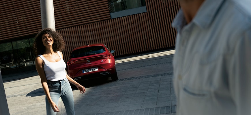 Seat leon parked with a couple nearby, ready to debunk common myths about hybrid electric vehicles