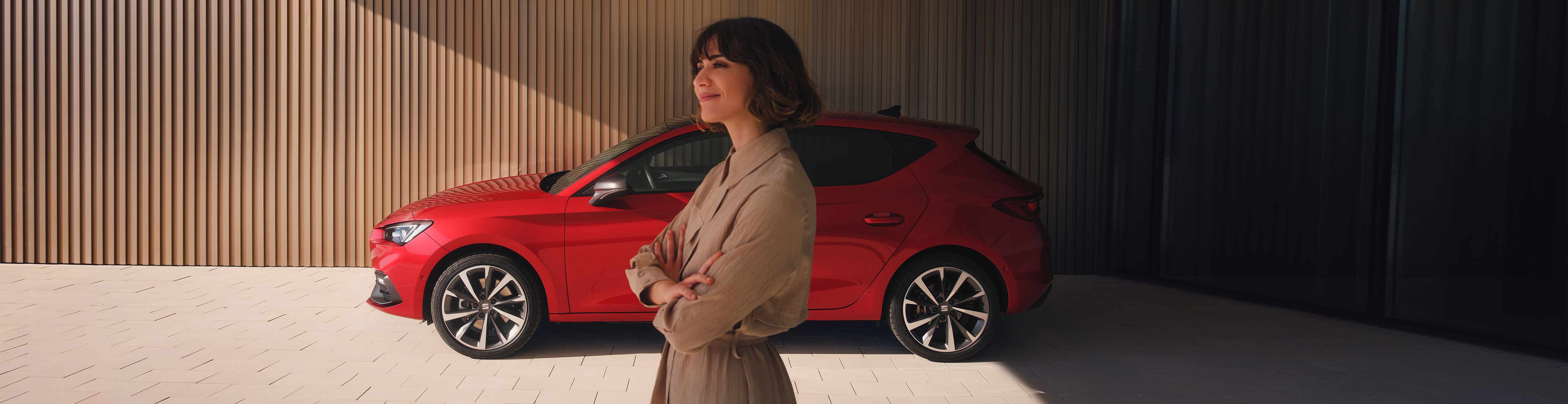 Kobieta stojąca obok SEATa Leon 5D w kolorze desire red 