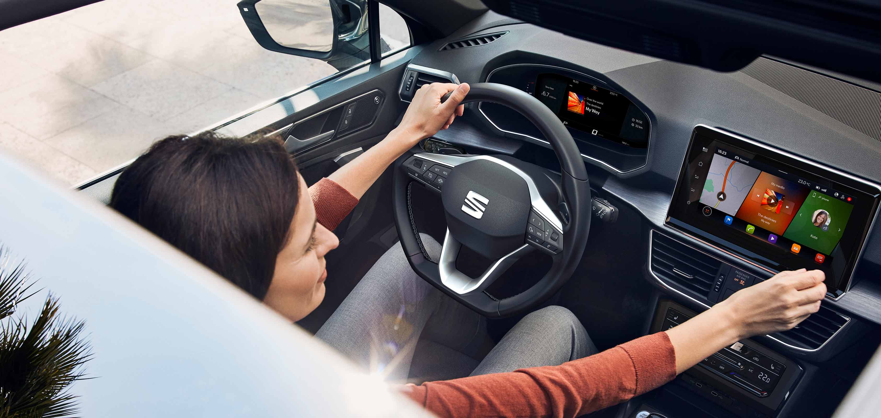 Zdjęcie z góry kobiety sterującej multimediami w SEAT-cie Tarraco