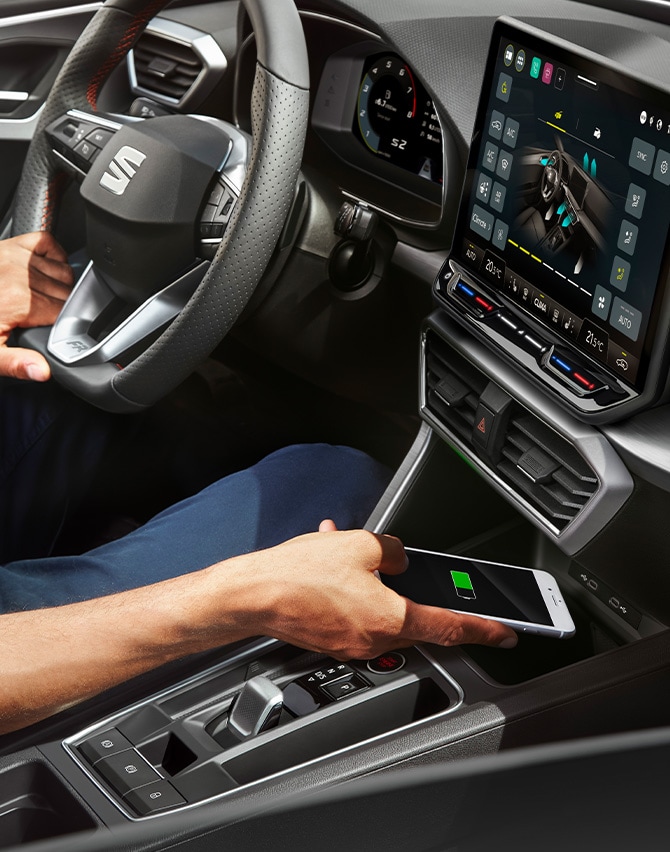 Mężczyzna ładujący swój telefon za pomocą ładowarki indukcyjnej wbudowanej w schowek SEAT-a Leon