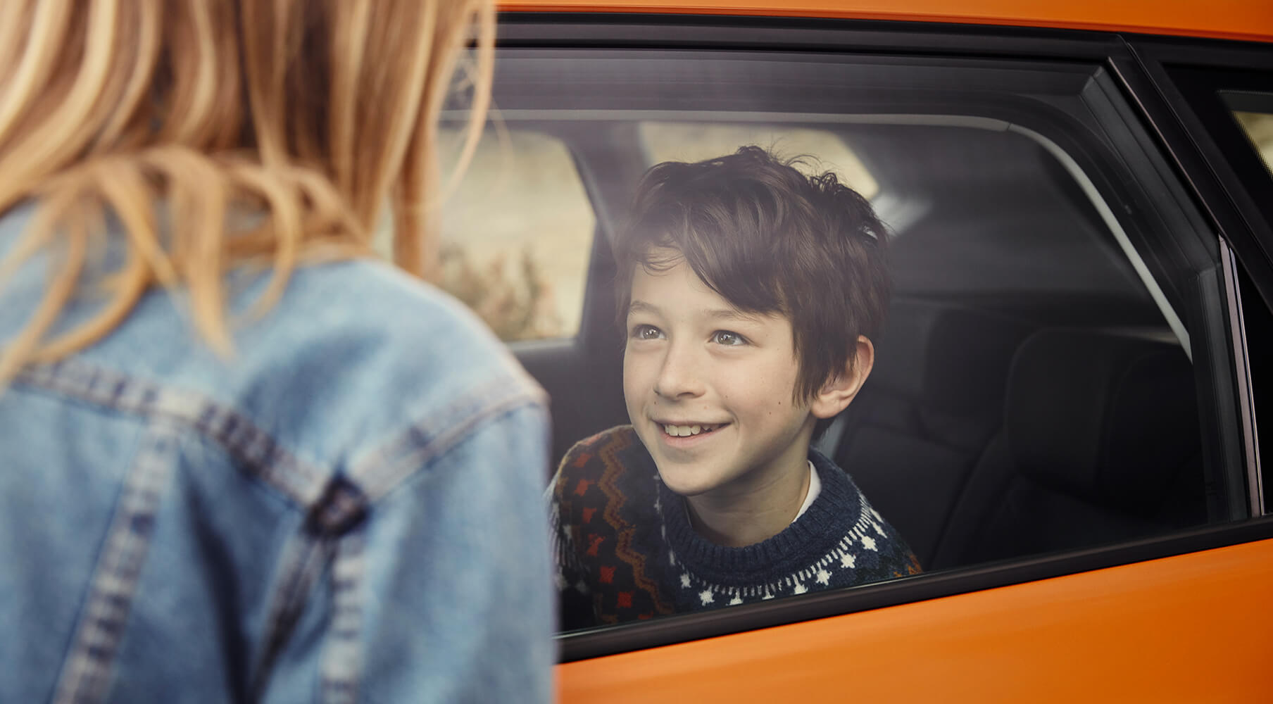 SEAT Serwis – przeglądy i konserwacja – chłopak uśmiechający się w samochodzie i kobieta stojąca na zewnątrz